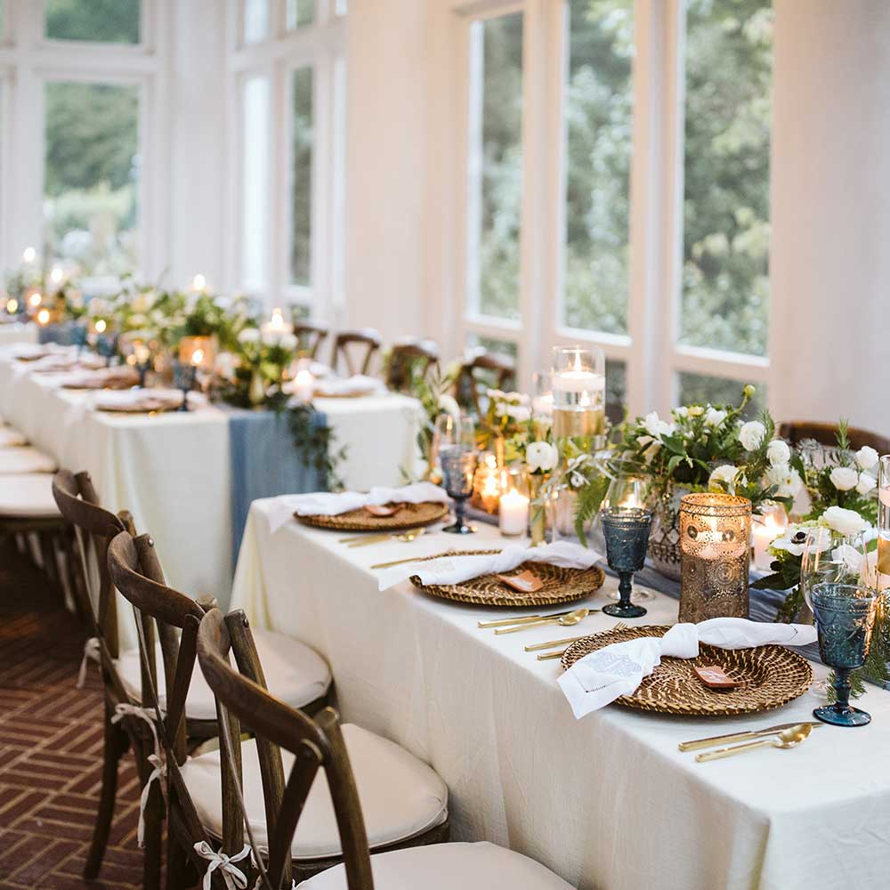 A formal dining setting with white tablecloths, candles, and flowers.