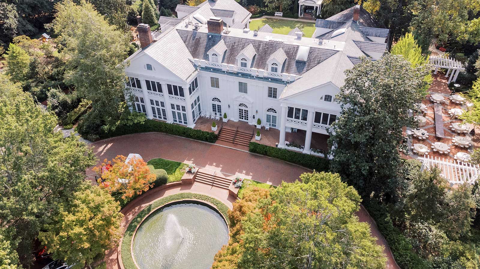 Aerial view of a large white mansion with a fountain and courtyard.