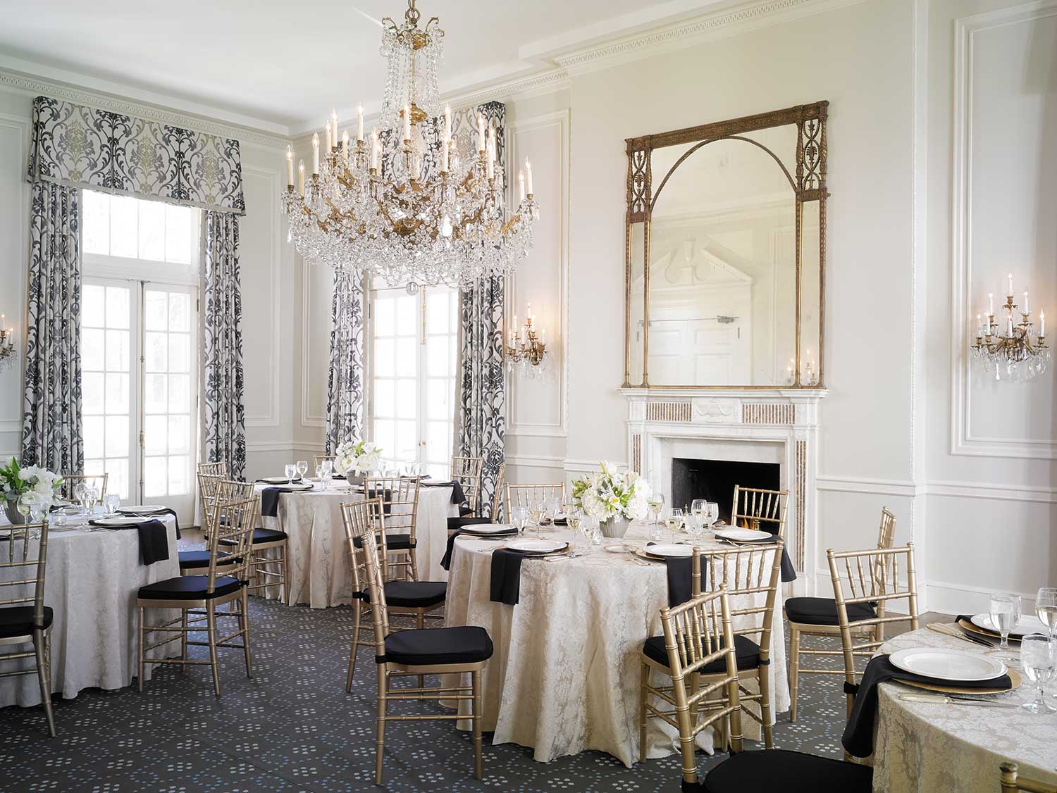 A formal dining room with a chandelier, fireplace, and mirror.